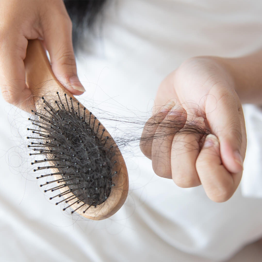 Woman pulling hair off of hairbrush