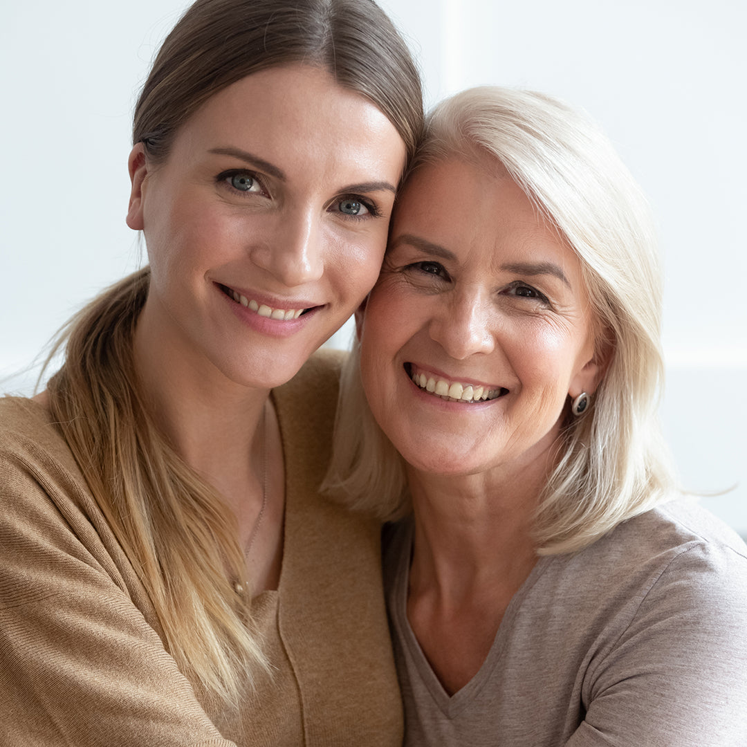 Two women closely embraced and smiling at the camera with flawless lashes and brows.