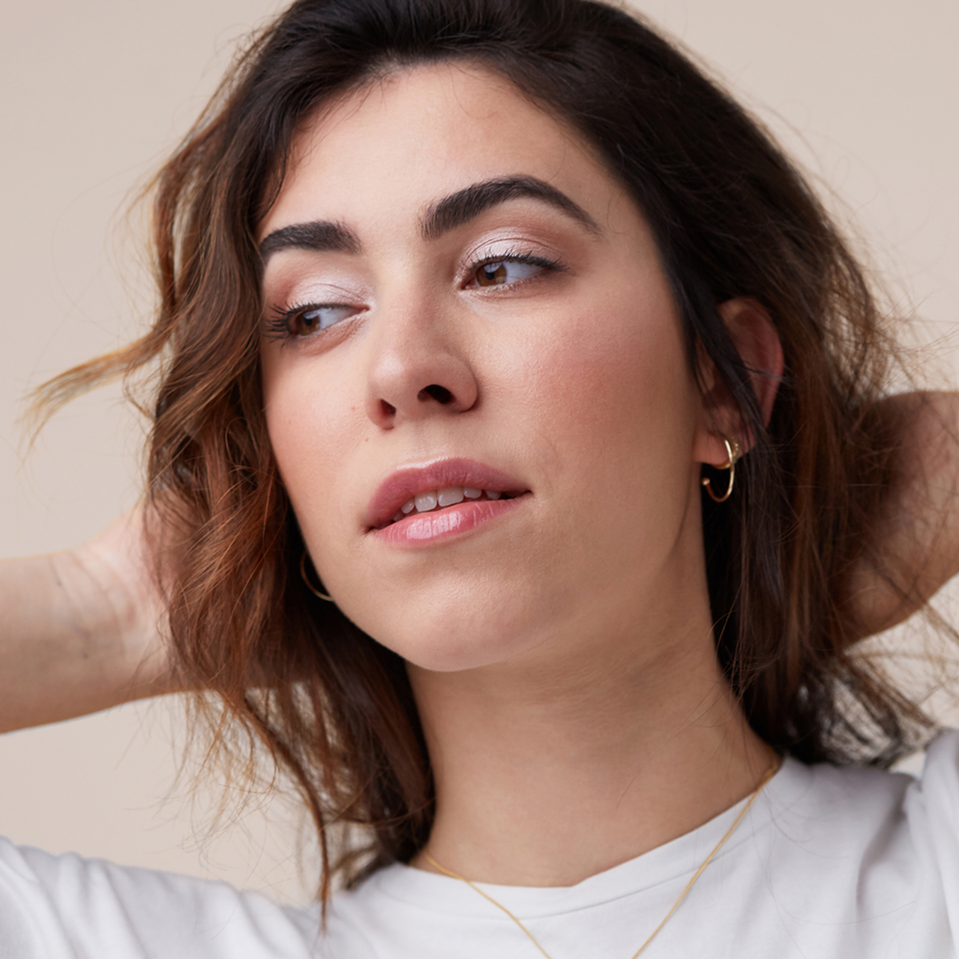 model with hands behind her head and full brows