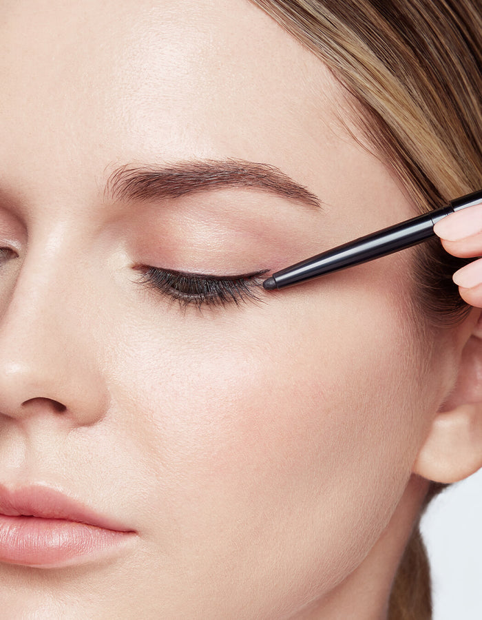 model applying Defining Liner Eyeliner on lash line