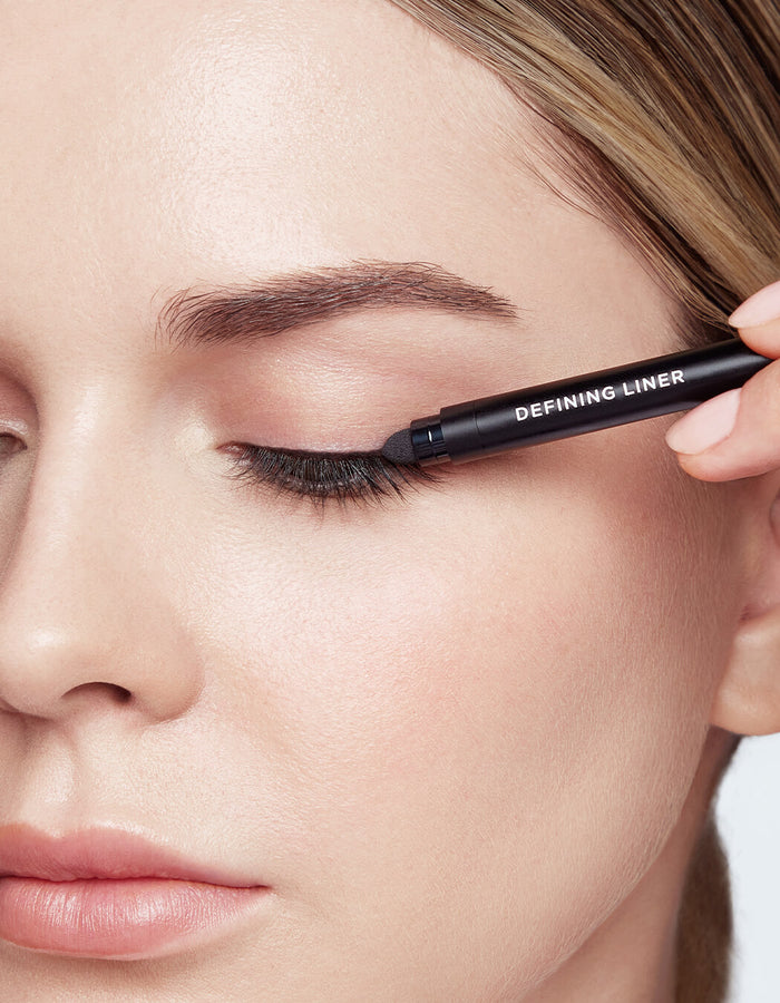 model applying Defining Liner Eyeliner on upper  lash line