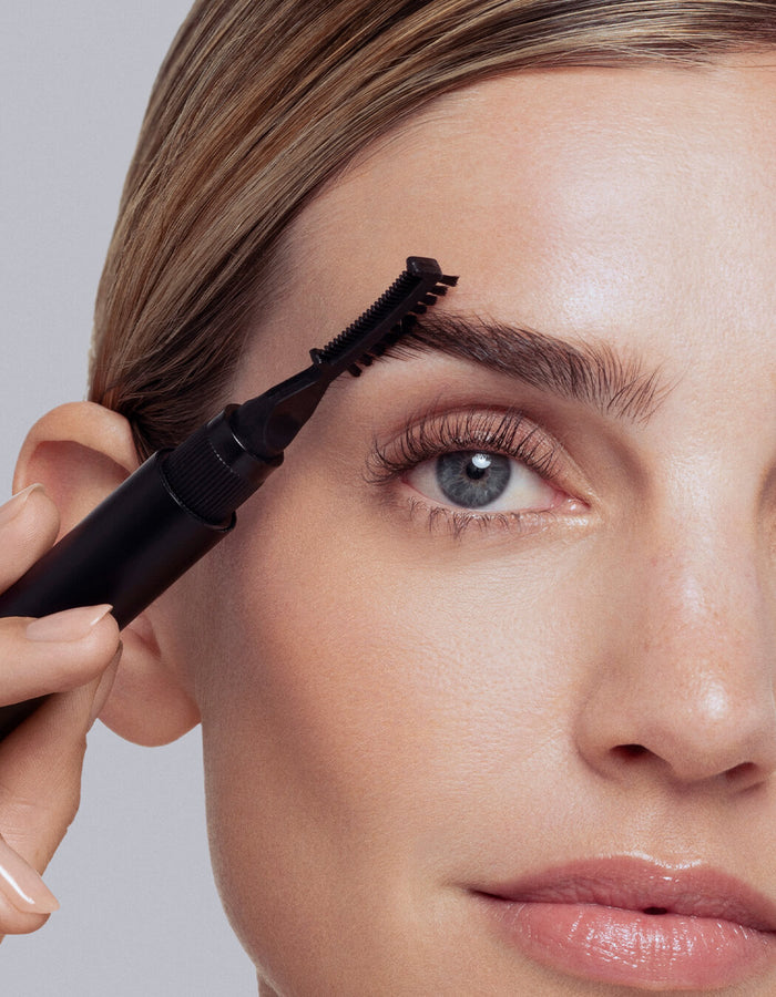 model grooming brows with applicator tool